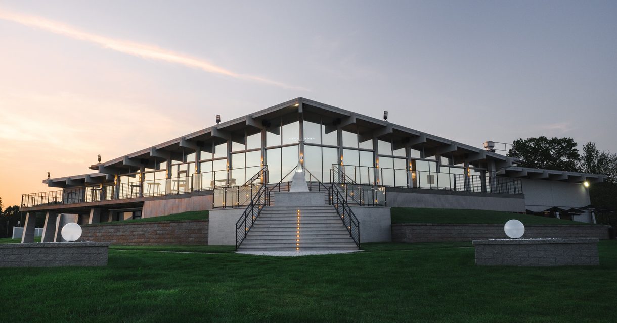 The VUE clubhouse and its grand staircase above a manicured lawn at sunset