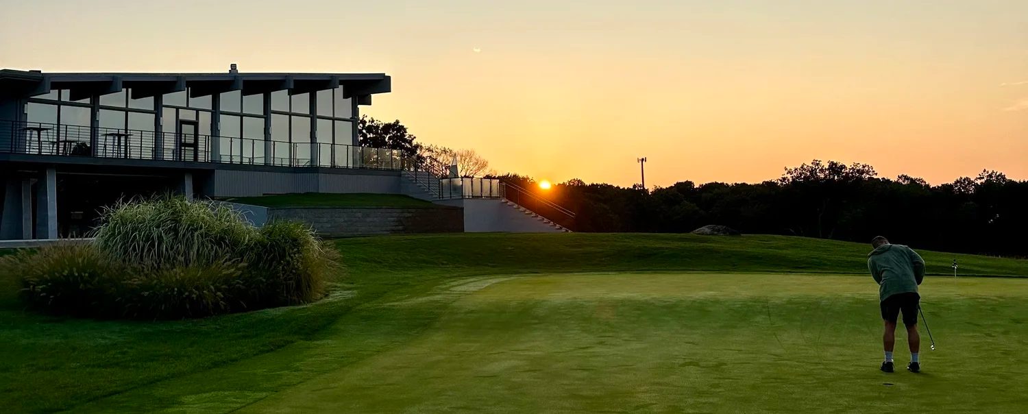 Golfer on the course at sunset with The VUE clubhouse in the background