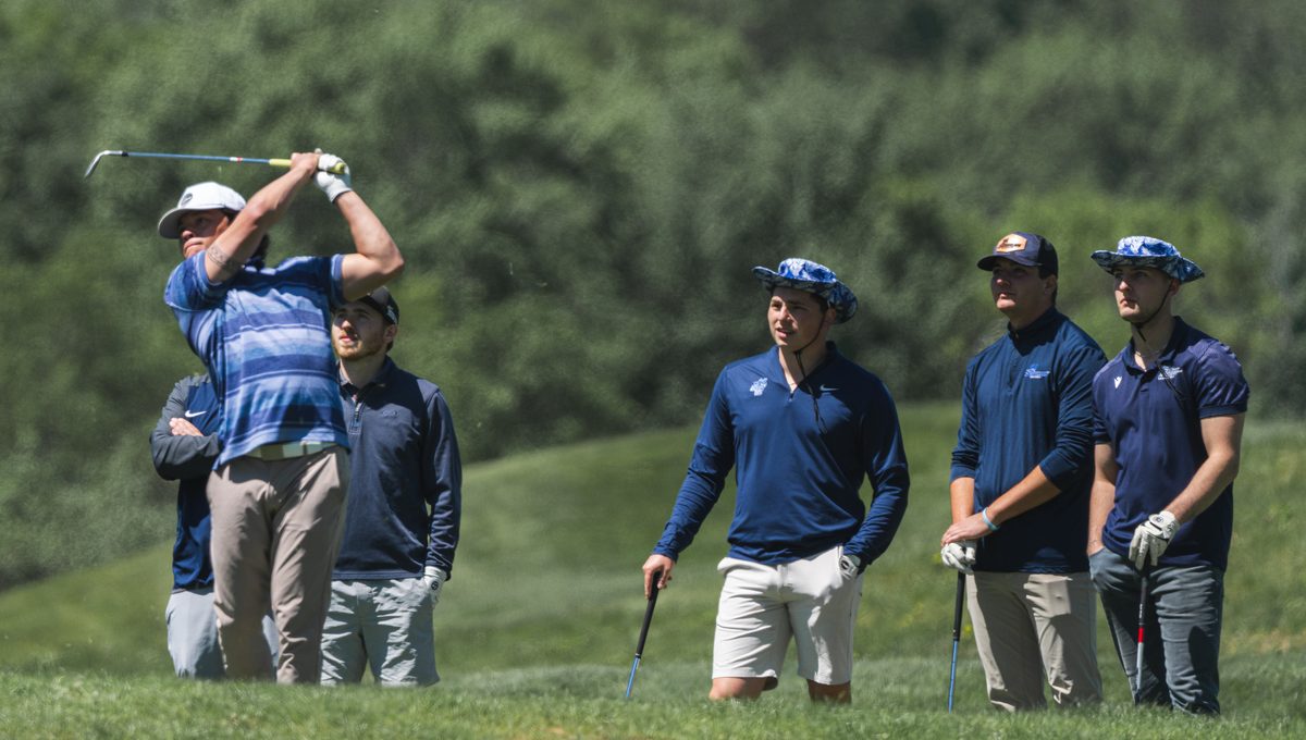 Golfer mid-swing as playing partners look on at The Links golf course at The VUE in Hamden, CT