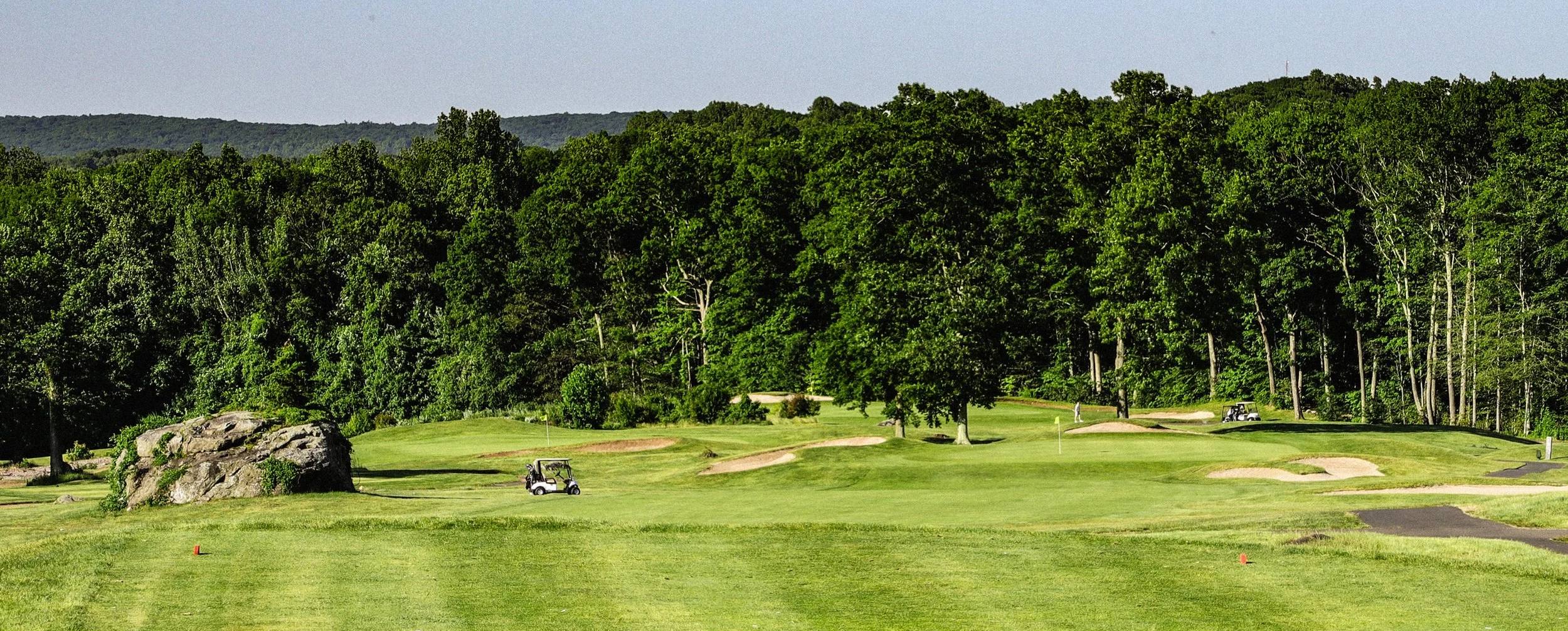 Open fairway and green lined with mature trees on The Links golf course at The VUE in Hamden, CT