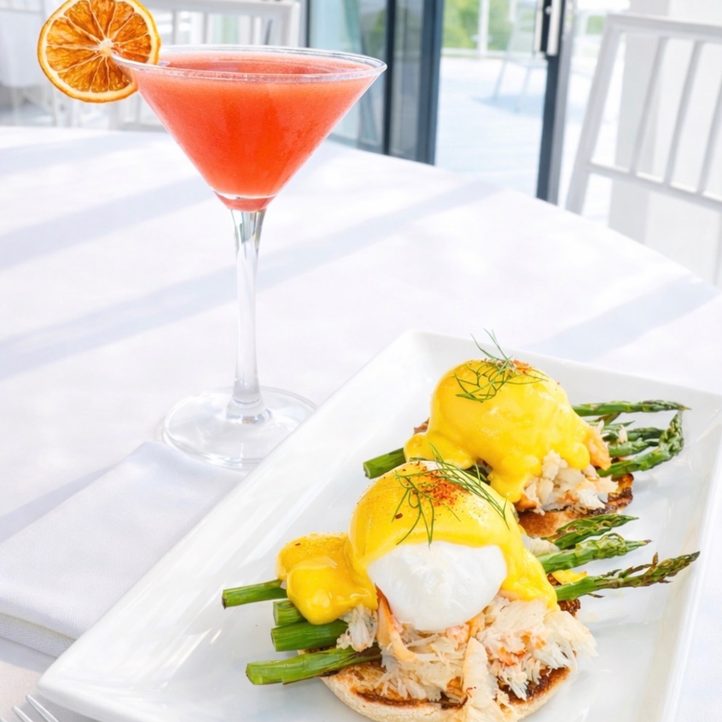 Crab eggs Benedict with asparagus and a grapefruit cocktail on a sunlit table at Nineteen