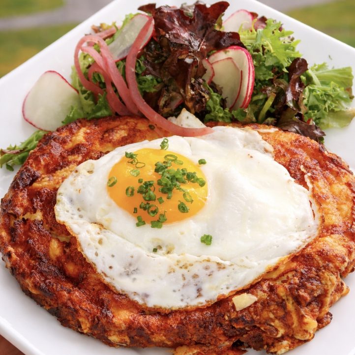 Golden hash brown with a sunny-side-up egg, chives and a radish and greens salad at Nineteen