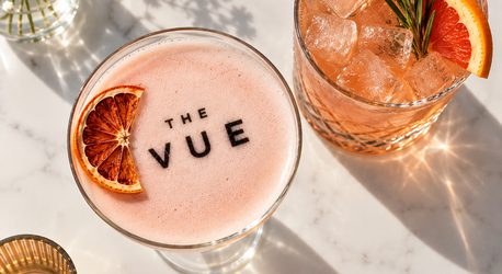 Signature cocktails at Nineteen, including a pink sour with The VUE logo in the foam