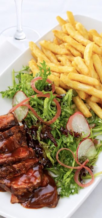 Sliced steak with barbecue glaze, french fries and a radish salad at Nineteen