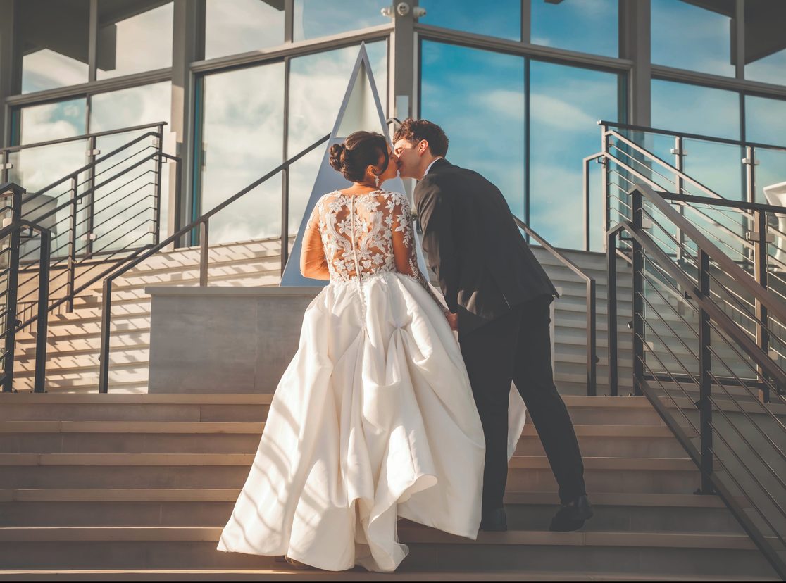 Bride and groom sharing a kiss on the outdoor staircase of The VUE clubhouse